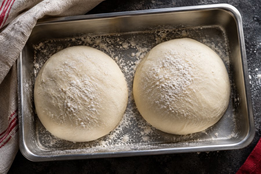 Fresh pizza dough in a proofing tray